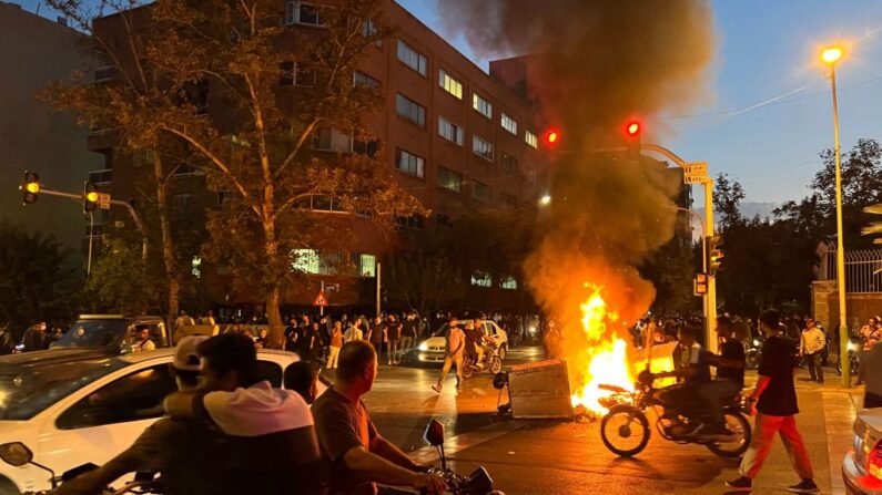 Une photo obtenue par l'AFP hors d'Iran montre des manifestants se rassemblant autour d'une barricade en feu lors d'une manifestation pour Mahsa Amini, une femme décédée après avoir été arrêtée par la "police des mœurs" de la République islamique, à Téhéran, le 19 septembre 2022. (Photo by -/AFP via Getty Images)