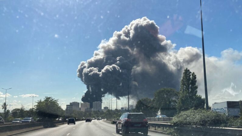 Des voitures roulent sur une autoroute alors qu'une épaisse fumée s'élève d'un bâtiment du Marche d'Interet National (MIN) à Rungis, le 25 septembre 2022. (AURORE MESENGE/AFP via Getty Images)