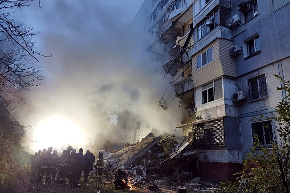 -Des sauveteurs se rassemblent devant un immeuble résidentiel endommagé après une frappe à Zaporizhzhia, le 9 octobre 2022. Photo de MARYNA MOISEYENKO/AFP via Getty Images.
