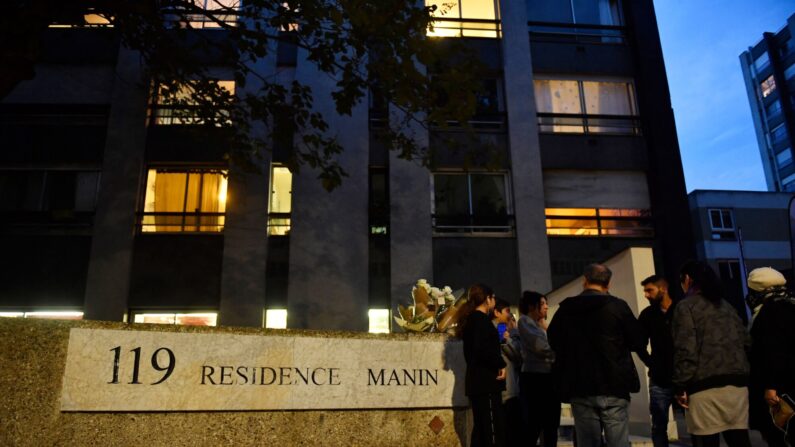 Des personnes se recueillent, le 15 octobre 2022, au pied de l'immeuble de Lola, 12 ans, retrouvée morte la veille, dans une malle, dans le 19e arrondissement de Paris. (Photo par JULIEN DE ROSA/AFP via Getty Images)