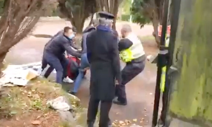 Capture d'écran d'une vidéo montrant un officier de police essayant de secourir un manifestant de Hong Kong battu au consulat chinois à Manchester, en Angleterre, le 16 octobre 2022. (Capture d'écran/Hong Kong Indigenous Defence Force via Epoch Times)