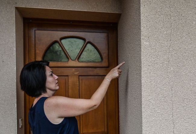 Sandrine Orts, membre de l'association "Oubliés de la canicule", montre des fissures sur les murs de sa maison, le 14 août 2019 à Savigny-en-Revermont, dans le centre de la France.       (Photo : PHILIPPE DESMAZES/AFP via Getty Images)