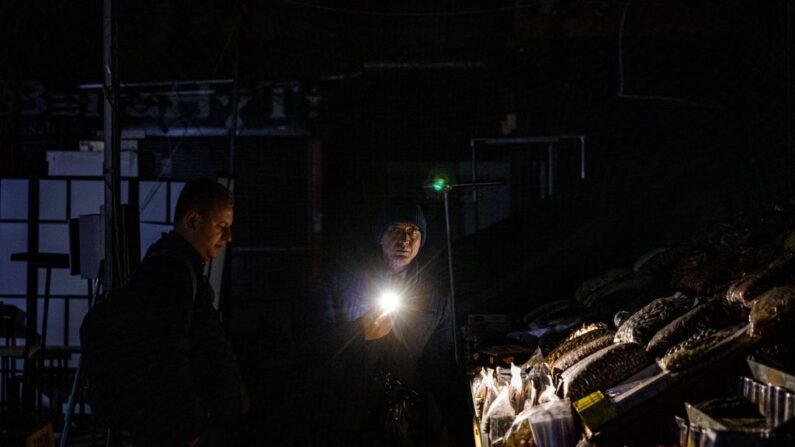 Un vendeur montre ses marchandises à un client lors d'une coupure de courant au marché Bessarabsky, dans le centre de Kiev, le 10 novembre 2022. (Photo: DIMITAR DILKOFF/AFP via Getty Images)