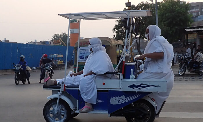 Des moines jaïns roulent sur un véhicule électrique le long d'une rue à Ahmedabad, en Inde, le 20 novembre 2021. (Sam Panthaky/AFP via Getty Images)