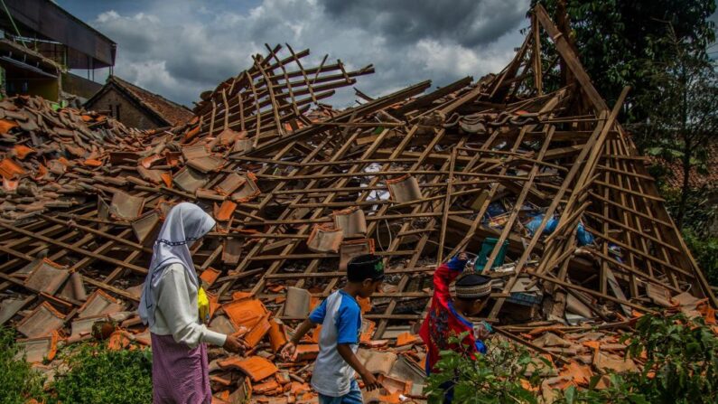 Des enfants de sinistrés passent devant une maison effondrée dans le village de Cugenang à Cianjur, dans l'ouest de Java, le 1er décembre 2022. (Photo: ADITYA AJI/AFP via Getty Images)