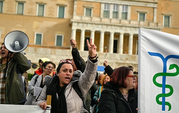 Des travailleurs de la santé scandent des slogans devant le Parlement grec à Athènes pendant leur arrêt de travail pour protester contre le projet de loi du gouvernement sur les hôpitaux publics actuellement discuté au Parlement, qui augmente selon eux la privatisation des services de santé publics, le 1er décembre 2022. (Photo : LOUISA GOULIAMAKI/AFP via Getty Images)