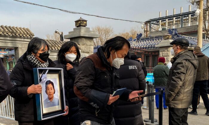 Des proches tiennent la photo d'une proche dans un crématorium à Pékin, le 20 décembre 2022. (Noel Celis/AFP via Getty Images)