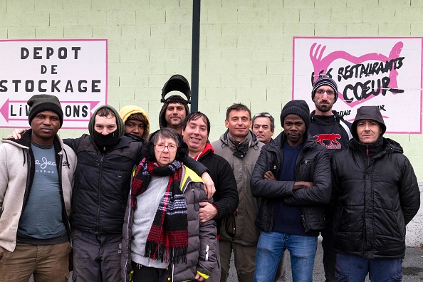 Des salariés et des bénévoles de l'association caritative Les Restos du cœur devant les locaux de l'organisation à Montluçon. (Photo : THIERRY ZOCCOLAN/AFP via Getty Images)