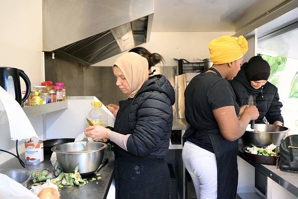 Des femmes cuisinent dans un camion aménagé en cuisine mobile à Marseille. (NICOLAS TUCAT/AFP via Getty Images)