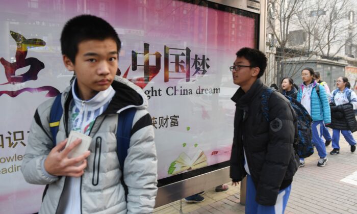 Des enfants passent devant un panneau de propagande sur le "rêve chinois" - un slogan associé au dirigeant chinois Xi Jinping – posé près d’une école à Pékin, le 12 mars 2018. (Greg Baker/AFP via Getty Images)