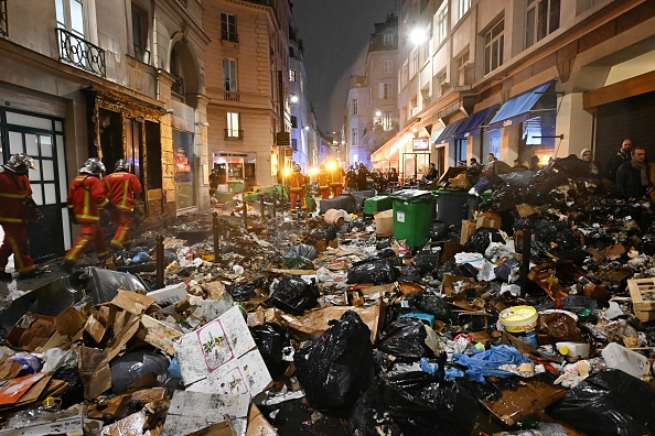 Des pompiers vérifient les déchets après avoir éteint un incendie à Paris, le 23 mars 2023. (STEFANO RELLANDINI/AFP via Getty Images)