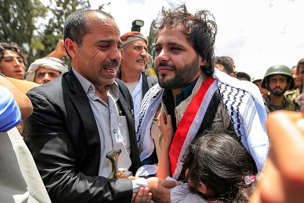 Un homme et une fille embrassent l'un des prisonniers huthis à l'aéroport international de Sanaa, le 14 avril 2023. (MOHAMMED HUWAIS/AFP via Getty Images)