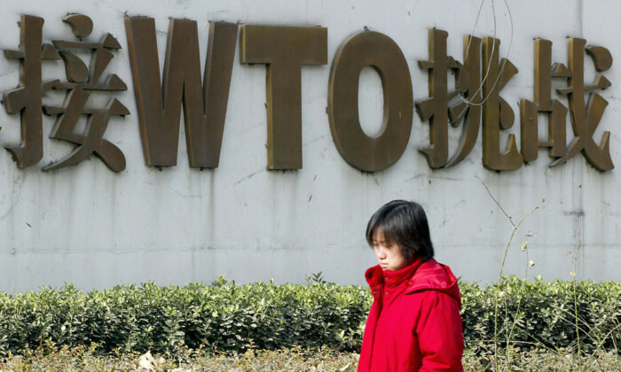 Dans une rue de Pékin, une Chinoise passe devant un panneau vantant l'adhésion de la Chine à l'Organisation mondiale du commerce (OMC), le 19 décembre 2003. (Goh Chai Hin/AFP/Getty Images)