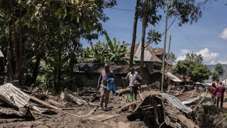 Sur des maisons englouties, des jeunes essaient de récupérer ce qui peut encore l'être : des tôles, des structures métalliques, des planches... (Photo GUERCHOM NDEBO/AFP via Getty Images)