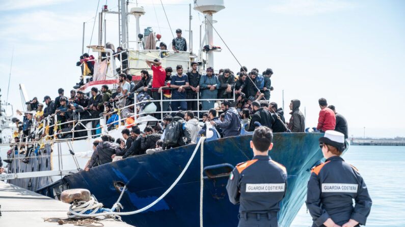 Deux gardes-côtes surveillent l'accostage du bateau de pêche avec 600 migrants à bord dans le port de Catane, le 12 avril 2023, en Italie. (Photo by Fabrizio Villa/Getty Images)