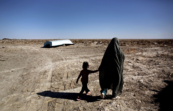 Une femme iranienne marche avec sa fille devant un bateau abandonné dans le village de Sikh Sar dans la zone humide de Hamoon, Sistan-Baloutchistan, à la frontière de l'Afghanistan, le 2 février 2015. (BEHROUZ MEHRI/AFP via Getty Images)