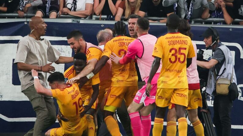 Le milieu de terrain français de Rodez Lucas Buades (2e-L) célèbre avec ses coéquipiers après avoir marqué un but alors qu'un spectateur se bagarre avec les joueurs après avoir pénétré sur le terrain. (Photo THIBAUD MORITZ/AFP via Getty Images)