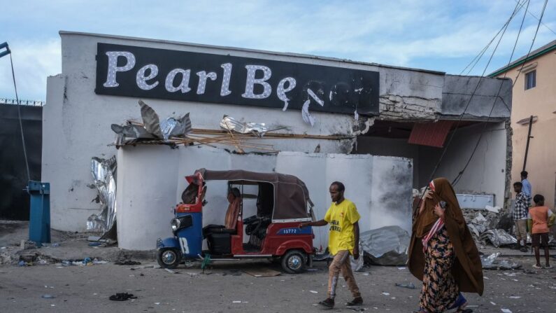 Des habitants passent devant un véhicule endommagé à l'extérieur du site d'une attaque à l'hôtel Pearl Beach à Mogadiscio, le 10 juin 2023. (HASSAN ALI ELMI/AFP via Getty Images)