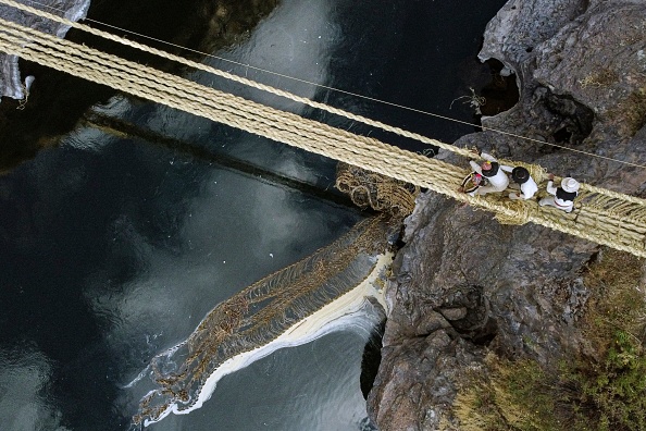 Des personnes participent à la rénovation annuelle du pont de paille Q'eswachaka, alors que l'ancien est emporté par la rivière Apurimac, au Pérou, le 9 juin 2023. (CHRISTIAN SIERRA/AFP via Getty Images)