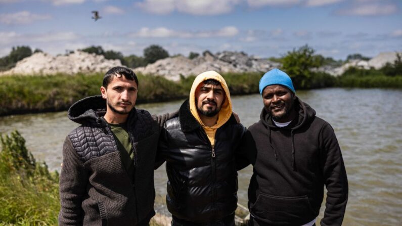 Adam (à g.) et Mehmet (au c.), migrants turcs, posent pour une photo avec un ami érythréen (à dr.) dans un camp de migrants improvisé à Loon-Plage, le 5 juin 2023. (Photo SAMEER AL-DOUMY/AFP via Getty Images)