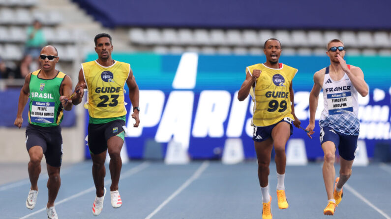 Felipe de Souza Gomes (Brésil) et son guide Jonas de Lima Silva (à g.) et Timothée Adolphe (France) et son guide Jeffrey Lami, participent à la finale du 400m T11 des Mondiaux de para athlétisme, le 12 juillet 2023 à Paris. (Photo Alexander Hassenstein/Getty Images)