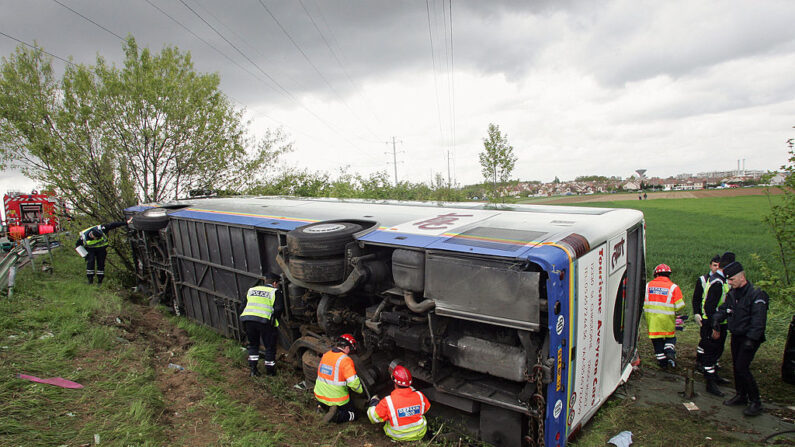 Des policiers, des pompiers et du personnel d'urgence se tiennent à côté d'un bus accidenté transportant 15 touristes japonais, le 25 avril 2005 sur l'autoroute A13 à côté de Versailles, à l'ouest de Paris. (Photo : PIERRE VERDY/AFP via Getty Images)