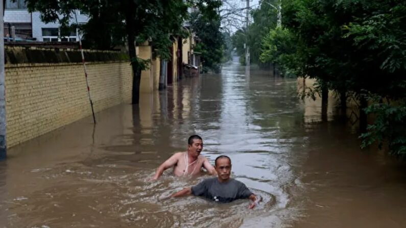 Des habitants se débattent dans des eaux profondes et rapides pour rejoindre un bateau de secouristes dans une zone inondée près de Zhuozhou, dans la province de Hebei, au sud de Pékin, le 3 août 2023. (Kevin Frayer/Getty Images)