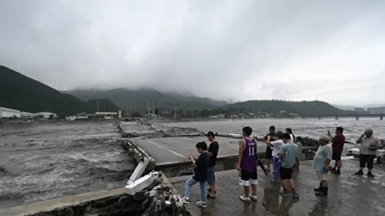 Des personnes observent l'effondrement d'un pont sur la rivière Dashihe suite à de fortes pluies dans le district de Fangshan à Pékin, le 1er août 2023. Au moins 11 personnes ont été tuées et 13 sont portées disparues après les fortes pluies qui se sont abattues sur Pékin, ont annoncé les médias d'État le 1er août, avec des averses qui ont submergé les routes et inondé les quartiers de boue. (Photo par Pedro PARDO/AFP via Getty Images)