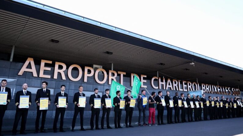 Des pilotes de Ryanair tiennent des pancartes « la loi est non-négociable » à l'aéroport de Charleroi, lors d'une grève des pilotes pour des raisons de conditions de travail. Le 14 août 2023. (Photo KENZO TRIBOUILLARD/AFP via Getty Images)