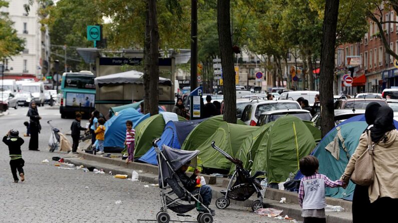 Des enfants jouent dans la rue à côté de tentes dans un campement sauvage où vivent des réfugiés et migrants syriens à la Porte de Saint-Ouen à Paris, le 19 septembre 2015. (Photo FRANCOIS GUILLOT/AFP via Getty Images)