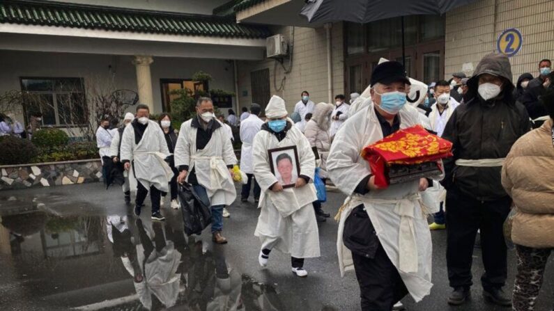 Une personne en deuil porte les restes incinérés d'un être cher alors qu'elle et d'autres participants portent des vêtements funéraires blancs traditionnels lors d'un enterrement à Shanghai, en Chine, le 14 janvier 2023. Le système de santé chinois s'efforce de faire face à une recrudescence des infections par le Covid-19 depuis que le gouvernement a mis fin à près de trois ans de contrôles stricts du Covid. (Kevin Frayer/Getty Images)