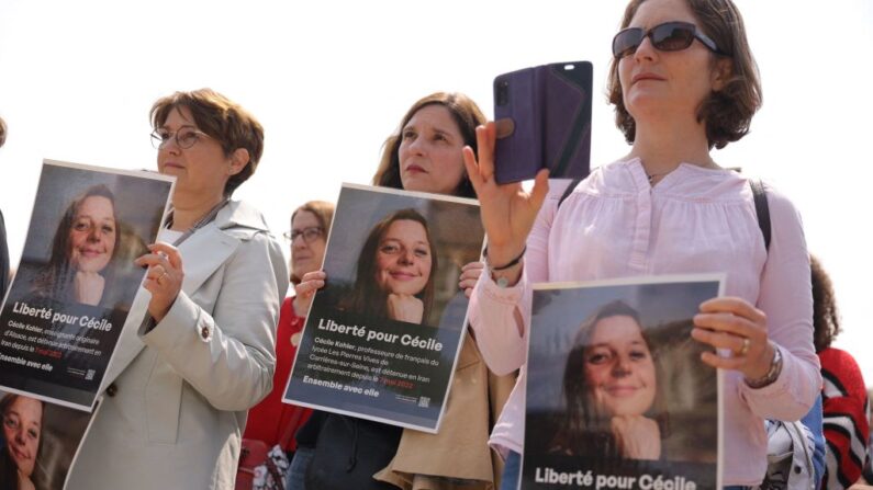 Des parents, des amis et des sympathisants tiennent des portraits de l'enseignante française Cécile Kohler, détenue avec son compagnon Jacques Paris en Iran, lors d'un rassemblement en leur faveur à Paris le 14 mai 2023. (Photo THOMAS SAMSON/AFP via Getty Images)