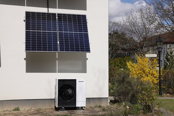 Une pompe à chaleur se trouve sous des panneaux solaires dans une maison. Illustration. (Photo by Sean Gallup/Getty Images)