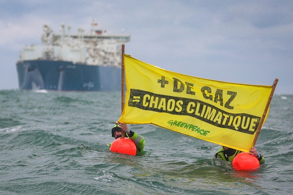 Des militants de Greenpeace France brandissant une banderole intitulée "Plus de gaz = chaos climatique", à proximité du terminal GNL TotalEnergies Cape Ann. (Photo LOU BENOIST/AFP via Getty Images)