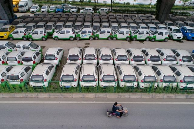 Un motocycliste passe devant de nouveaux véhicules électriques garés dans un parking sous un viaduc à Wuhan, dans la province du Hubei (centre de la Chine), le 22 mai 2017. (STR/AFP via Getty Images)