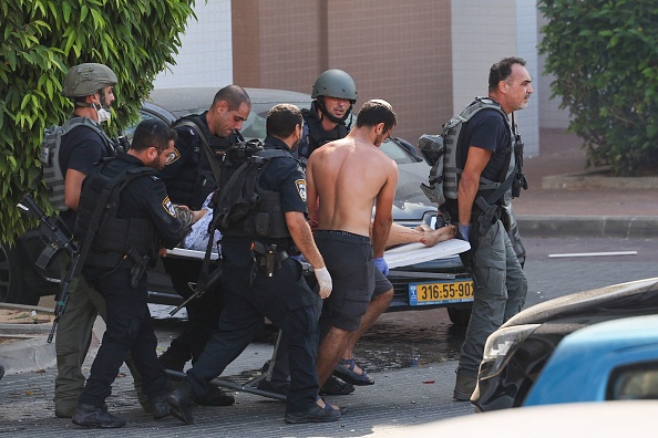 Des membres des forces de sécurité israéliennes transportent une personne blessée depuis la bande de Gaza à Ashkelon, le 7 octobre 2023. (Photo AHMAD GHARABLI/AFP via Getty Images)