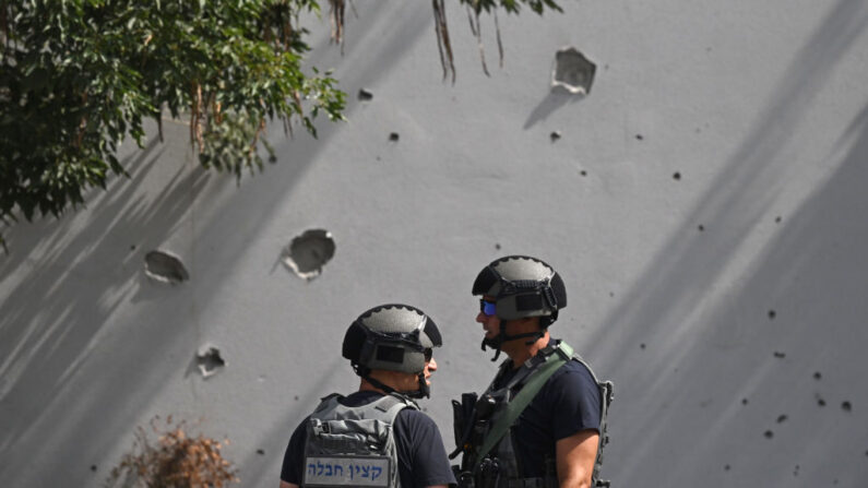 Des soldats israéliens observent les dégâts causés par des éclats d'obus sur un mur après un tir de roquette le 12 octobre 2023 à Sderot, en Israël. (Photo: Leon Neal/Getty Images)