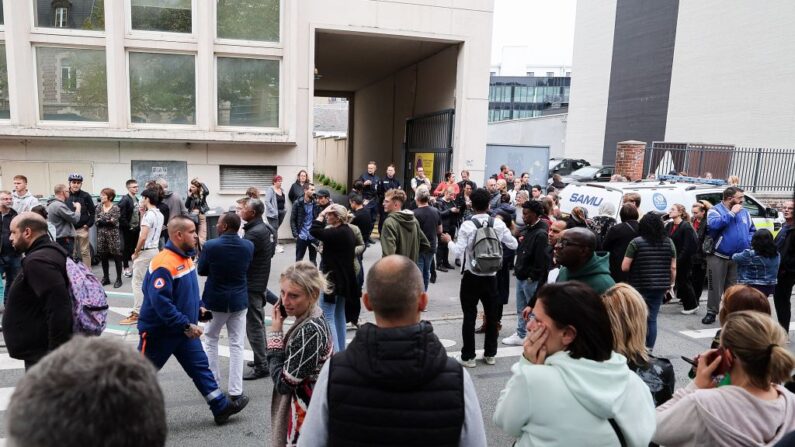 Des personnes se tiennent devant l'entrée du lycée Gambetta à Arras, le 13 octobre 2023, où un enseignant a été tué et deux autres personnes grièvement blessées lors d'une attaque au couteau. (Photo: FRANCOIS LO PRESTI/AFP via Getty Images)