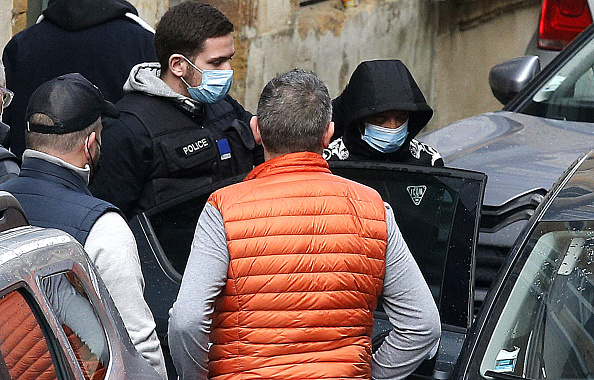 Un suspect (à dr.) sort d'un bâtiment après avoir assisté à une reconstitution de la séquence des événements sur les lieux où le corps de Loana, 10 ans, a été retrouvé dans une cave la veille au soir. (Photo FRANÇOIS NASCIMBENI/AFP via Getty Images)