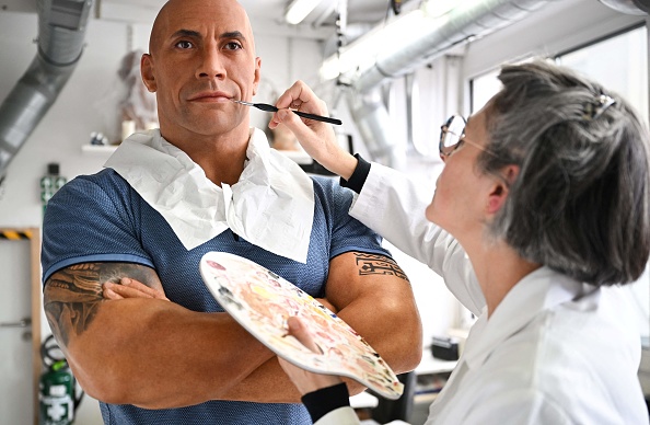 Un employé ajuste le teint de l'effigie en cire de Dwayne Johnson, après que l'acteur américain se soit plaint de son teint pâle, au musée Grévin à Paris, le 24 octobre 2023. (Photo STEFANO RELLANDINI/AFP via Getty Images)