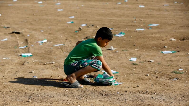 Un garçon palestinien ramasse des tracts largués par l'armée israélienne, à l'est de la ville de Gaza, le 14 mai 2018. (Photo MOHAMMED ABED/AFP via Getty Images)