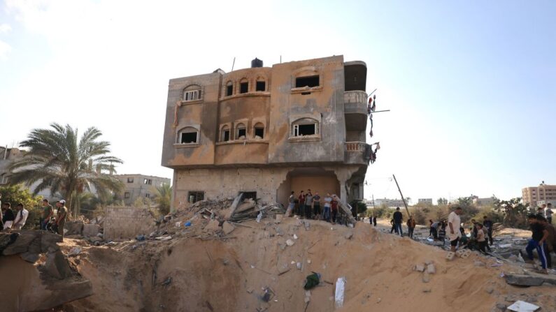 Des Palestiniens se tiennent à côté d'un cratère provoqué par l'explosion d'une frappe aérienne israélienne à Khan Yunis, dans le sud de la bande de Gaza, le 16 octobre 2023. (Photo par MAHMUD HAMS/AFP via Getty Images)