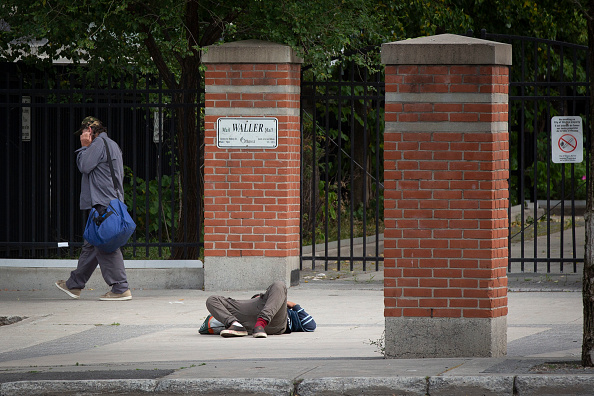 Un piéton passe devant une personne ayant consommé de la drogue à Ottawa, Ontario, le 25 juin 2020. (Photo LARS HAGBERG/AFP via Getty Images)