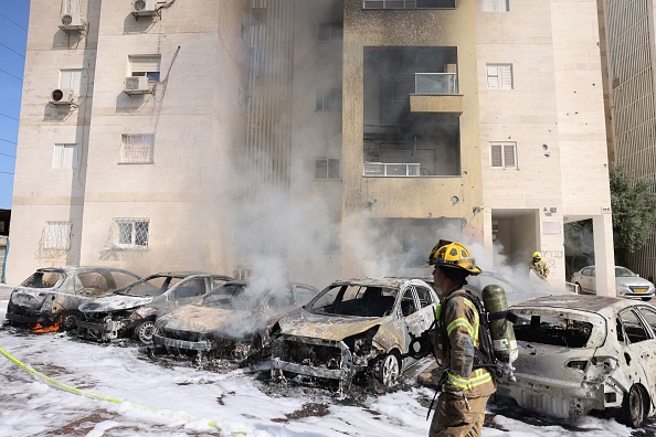  Des équipes de pompiers israéliens éteignent le feu dans un parking à l'extérieur d'un immeuble résidentiel à la suite d'une attaque à la roquette depuis la bande de Gaza dans la ville d'Ashkelon, dans le sud d'Israël, le 7 octobre 2023. (Photo AHMAD GHARABLI/AFP via Getty Images)