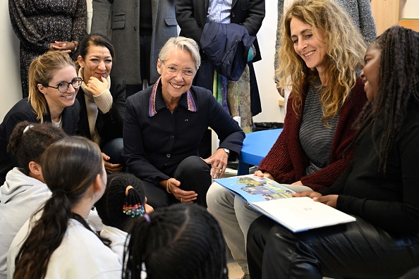 La Première ministre Élisabeth Borne (au c.) et la ministre des Solidarités Aurore Berge (à g.) rencontre les enfants lors de la visite d'un centre social à Chanteloup-les-Vignes, le 27 octobre 2023. (Photo BERTRAND GUAY/POOL/AFP via Getty Images)