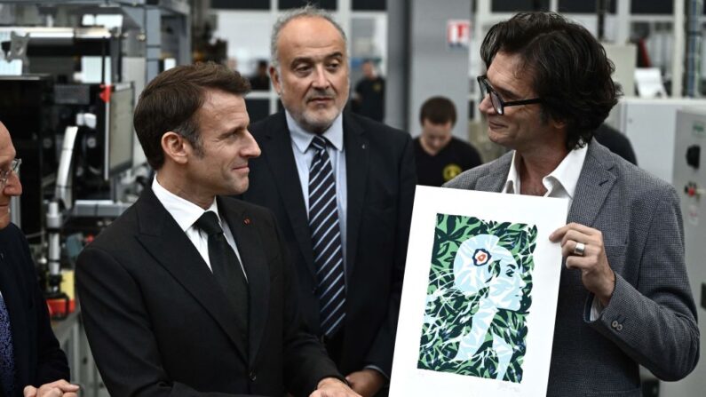 Emmanuel Macron, entouré du PDG du groupe « La Poste » Philippe Wahl (à g.) et du président de Philaposte Paul Dworkin (2e à dr.), se voit présenter par l'illustrateur français Olivier Balez (à dr.) le nouveau visage de Marianne, à Boulazac le 7 novembre 2023. (Photo PHILIPPE LOPEZ/POOL/AFP via Getty Images)