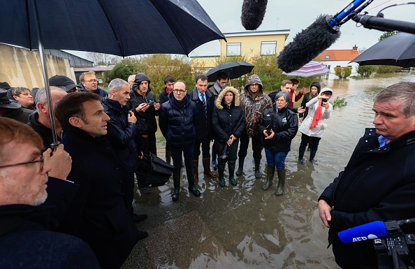 Le président Emmanuel Macron (2è à g.), entouré du ministre de l'Agriculture Marc Fesneau (à g.), discute avec un habitant lors d'une visite au Doulac près de Saint-Omer, le 14 novembre 2023. (Photo AURELIEN MORISSARD/POOL/AFP via Getty Images)