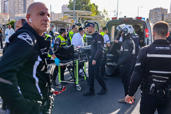 Des sauveteurs israéliens placent un corps sur un brancard sur le site d'une fusillade à Jérusalem qui a fait dix victimes, le 30 novembre 2023. (Photo MENAHEM KAHANA/AFP via Getty Images)