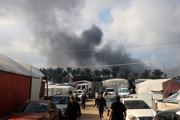 Des gens marchent dans un corridor de sécurité pour personnes déplacées alors que de la fumée s'élève après une frappe israélienne à Khan Yunis, dans le sud de la bande de Gaza, le 1er décembre 2023. (Photo MAHMUD HAMS/AFP via Getty Images)
