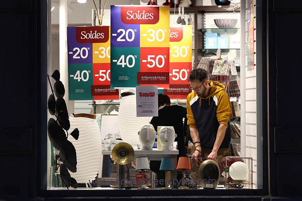 Un homme installe des présentoirs dans une vitrine pour les soldes d'hiver de la France à la veille de leur début officiel à Strasbourg. (Photo FREDERICK FLORIN/AFP via Getty Images)